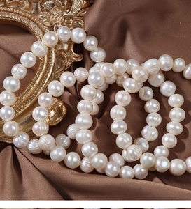 Close-up of white freshwater pearls on dark brown satin with a vintage gold frame