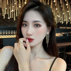Close-up of elegant gold tassel star earrings and butterfly ring on female model
