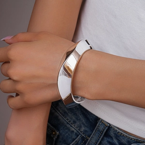 Close-up of a wide polished silver geometric cuff bracelet worn by a model