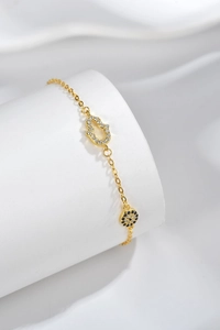 Macro detail of gold S925 silver Evil Eye and Hamsa Hand charms on a fine chain