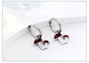 Macro shot of silver stainless steel hoop earrings featuring red mushroom charms