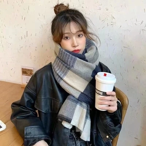 Close-up of blue and grey plaid scarf with soft fringe tassels worn in a cozy cafe setting