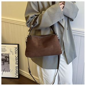 Detail of vintage brown suede shoulder bag with silver metallic buckle on grey blazer