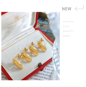 Detail view of two pairs of 18K gold-plated oval stud earrings in a red jewelry box
