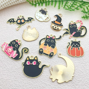 Flat lay of colorful enamel black cat and pumpkin charms for DIY Halloween jewelry making