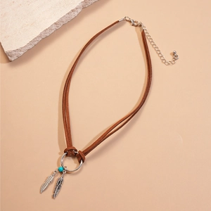 Detail of bohemian necklace with silver leaf pendants and a turquoise bead on brown cord