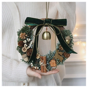 Detailed view of a Christmas wreath with green velvet bow, gold bells and pine cones