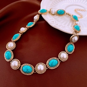 Collar vintage dorado con piedras turquesas y perlas sobre fondo de cuero oscuro