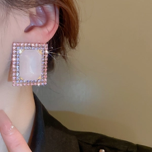 Close-up of vintage rectangular pink crystal stud earrings worn by a model