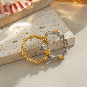 Two-tone gold and silver star rings with irregular rock texture on beige stone