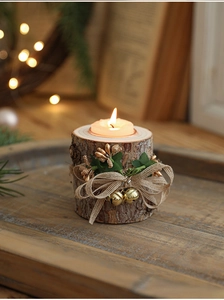 Close-up of rustic wooden candle holder with jute bow, golden bells and burning tealight