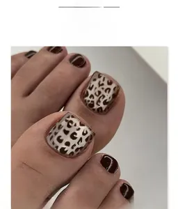 Macro shot of short square fake toenails with leopard print and solid brown finish