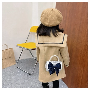 Close-up of girls tweed crossbody bag with velvet bow and faux pearl handle detail