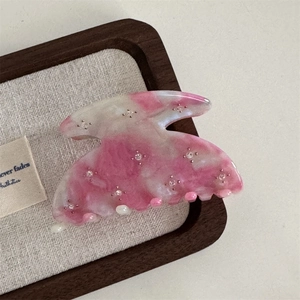 Close-up of pink marble acetate hair claw with sparkling rhinestone star embellishments