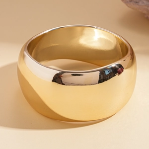 Close-up of polished gold wide cuff bracelet with a high-shine mirror finish surface