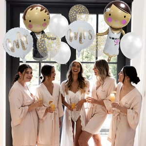 Close-up of Mr and Mrs wedding balloons with gold glitter text and bridal party backdrop