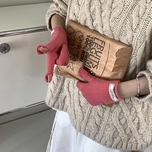 Detail of pink knitted fingerless gloves with woven label and soft thick winter texture