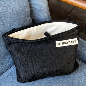 Detail of black rose jacquard cosmetic bag featuring a metal zipper and interior storage
