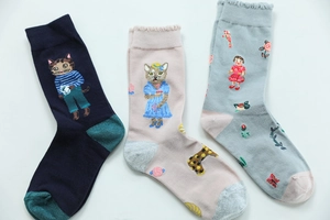 Detailed view of three cotton blend socks with cat and girl patterns in various colors