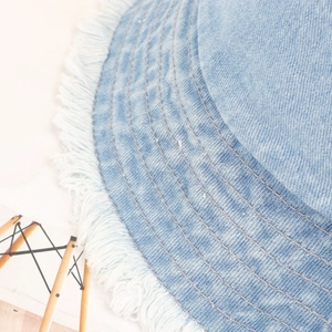 Detailed view of frayed edges and stitching on light blue washed denim bucket hat