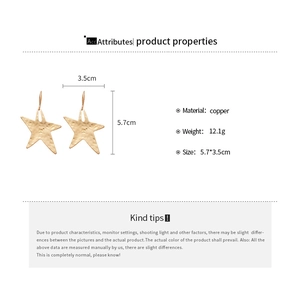 Detail view of gold star earrings with hammered texture and 5.7cm total length