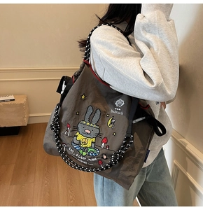 Detailed view of dark canvas tote bag featuring rabbit prints and woven rope strap