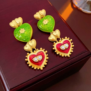 Detail of vintage heart earrings with green enamel and pearls on a brown wooden box