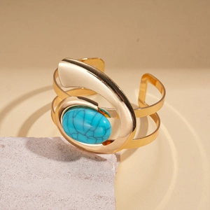 Detail of vintage gold-tone bangle featuring a large oval blue resin stone with texture