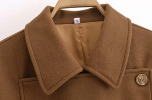 Detail of a brown wool coat lapel with size S label and button on a wooden hanger