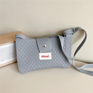 Detail of light blue knit crossbody bag showing diamond texture and metal magnetic snap