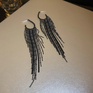 Détail de boucles d'oreilles à pompons en métal noir avec perles sur une table