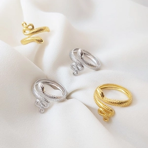 Detailed macro view of gold and silver snake rings with textured scales on white fabric
