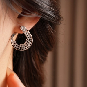 Macro shot of silver paved zircon flower huggie hoop earrings worn by a model