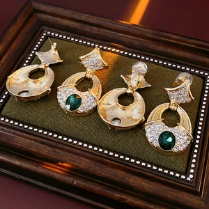 Detail of vintage gold earrings with green gemstone and rhinestones on velvet