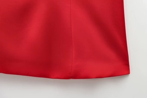 Gros plan détaillé d'un haut en satin rouge montrant les coutures fines et l'ourlet