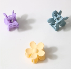 Detailed view of matte flower hair claws in purple, blue, and yellow with metal springs