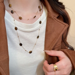 Close-up of golden layered necklace with brown tiger eye stone beads and matching ring