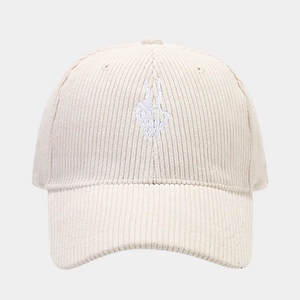 Close-up of corduroy texture and white skeleton hand embroidery on a beige baseball cap