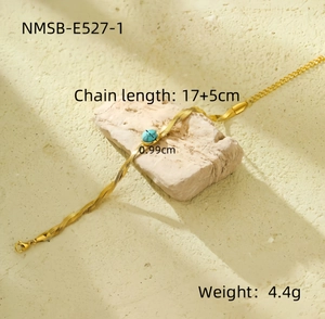 Detail of gold flat snake chain bracelet with blue textured bead on a stone prop