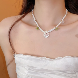 Detail of beaded pearl necklace with flower and shell pendants on a model