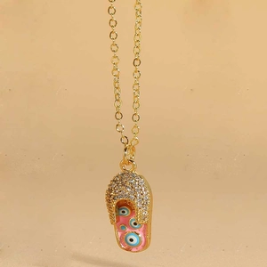 Detail of gold-plated flip-flop pendant with pink enamel and evil eye charms