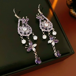 Macro shot of purple crystal butterfly flower drop earrings in a black gift box