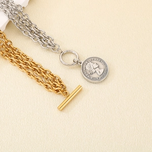 Macro detail of layered stainless steel bracelets with coin pendants and OT toggle clasp