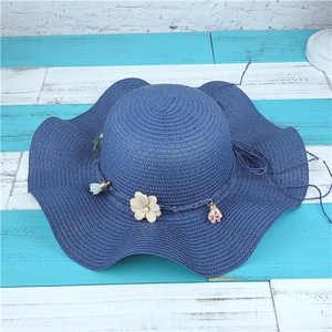Détail du chapeau de soleil bleu en paille tressée avec pendentifs de fleurs