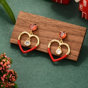 Detailed view of red heart earrings with zircon drops on a festive wooden display