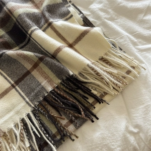 Detailed view of British style plaid scarf featuring soft cashmere texture and long fringe