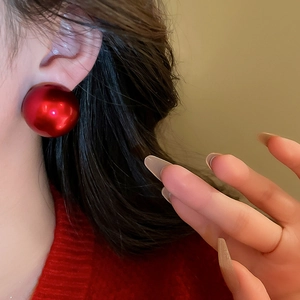 Detailed close-up of round red pearl earrings worn by a model for a stylish look