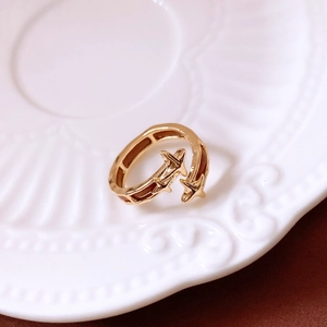 Detailed view of gold star open ring with triple cross stars on white porcelain plate