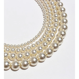 Elegant round cream white pearl necklaces in multiple sizes displayed in curved composition