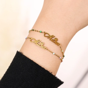 Close-up of golden Althea name bracelet with crown charm and colorful beads on a wrist